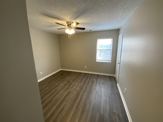 spare room with a textured ceiling, dark wood finished floors, a ceiling fan, and baseboards