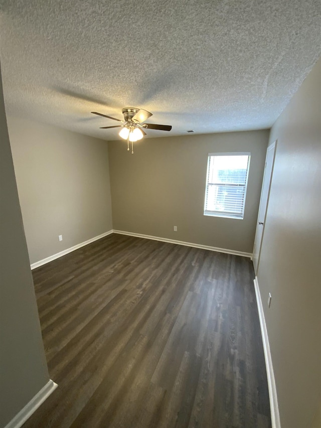 unfurnished room featuring dark wood-style floors, a textured ceiling, baseboards, and a ceiling fan