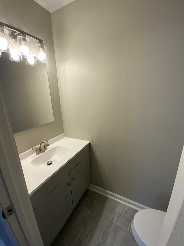 bathroom with toilet, baseboards, and vanity