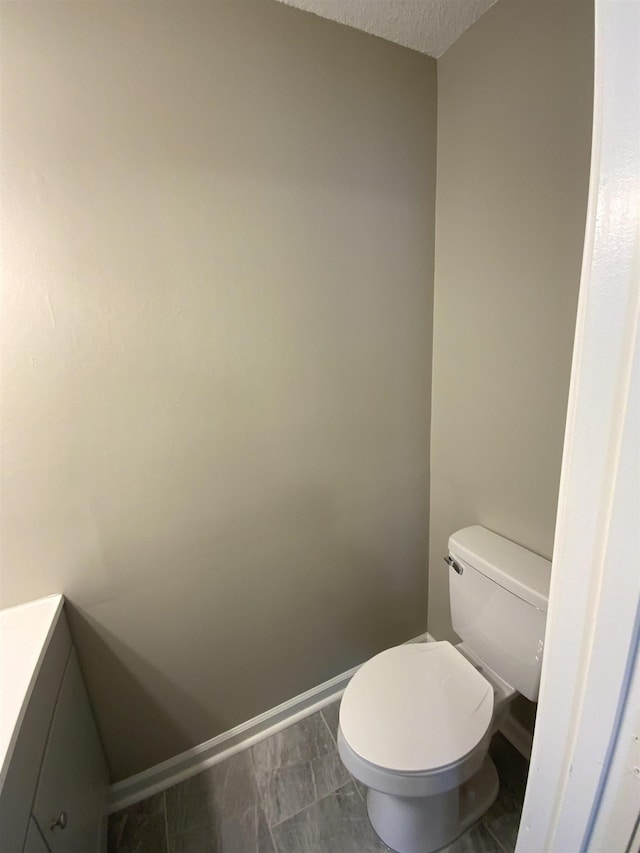 bathroom featuring toilet, baseboards, a textured ceiling, and vanity