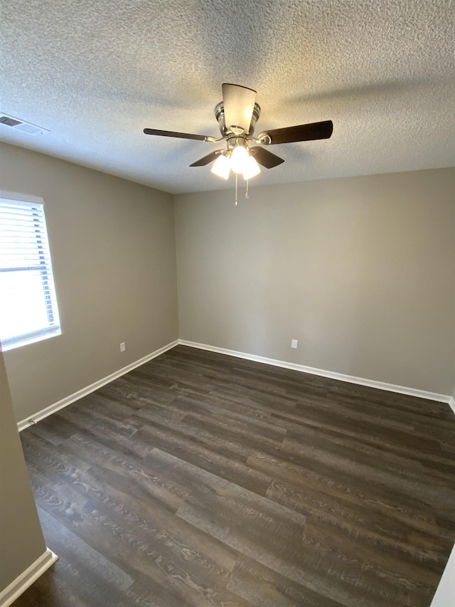 unfurnished room featuring ceiling fan, a textured ceiling, visible vents, baseboards, and dark wood finished floors