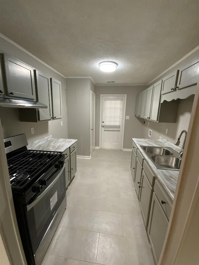 kitchen featuring gas stove, light countertops, a sink, and under cabinet range hood