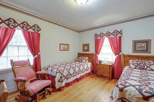 bedroom featuring ornamental molding, multiple windows, and hardwood / wood-style floors