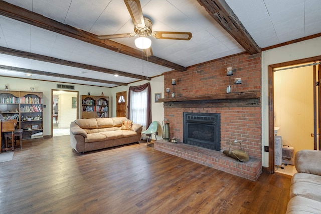 living area with wood finished floors, visible vents, a ceiling fan, a brick fireplace, and beamed ceiling