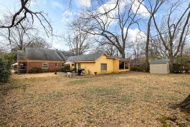 back of property featuring central AC unit, a lawn, an outbuilding, a shed, and brick siding