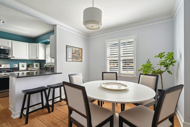 dining room with baseboards, light wood finished floors, and crown molding