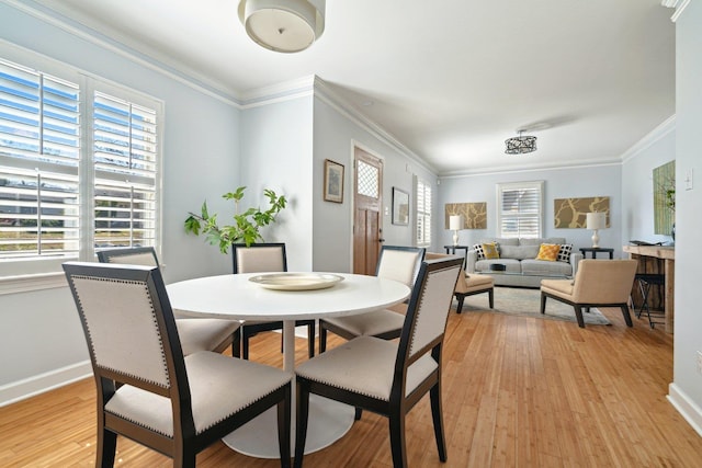 dining room with ornamental molding, light wood-style flooring, and baseboards