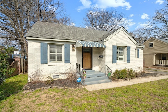 bungalow with crawl space, a shingled roof, fence, and brick siding