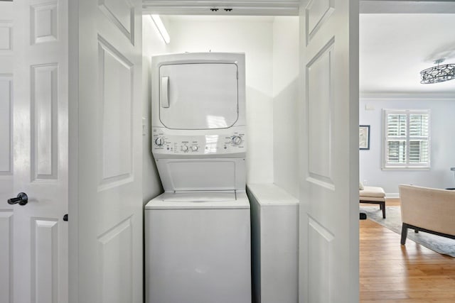 clothes washing area featuring stacked washer and dryer, laundry area, and light wood-style floors