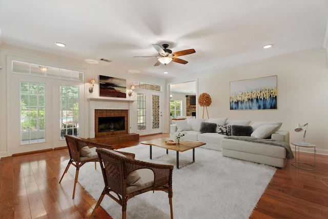 living area with a wealth of natural light, a fireplace, wood finished floors, and visible vents