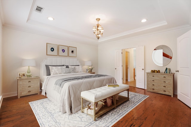 bedroom featuring a notable chandelier, wood finished floors, visible vents, ornamental molding, and a raised ceiling