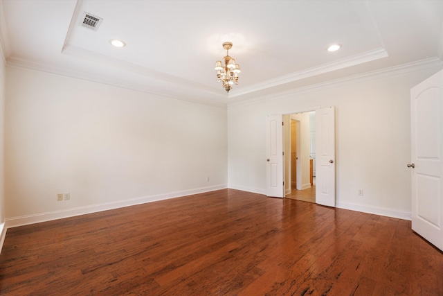 empty room with a tray ceiling, wood finished floors, visible vents, and an inviting chandelier