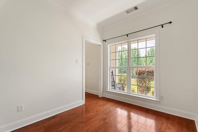 empty room featuring a wealth of natural light, wood-type flooring, visible vents, and crown molding