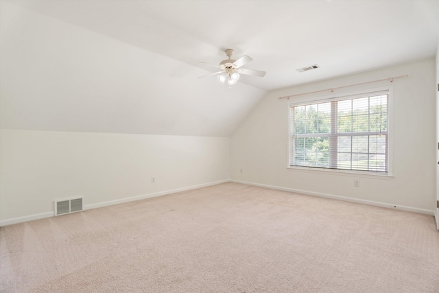 additional living space with light carpet, baseboards, visible vents, and lofted ceiling