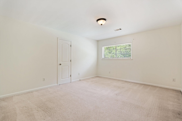 empty room with baseboards, visible vents, and light colored carpet