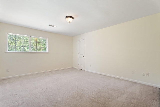 unfurnished room featuring visible vents, light carpet, and baseboards