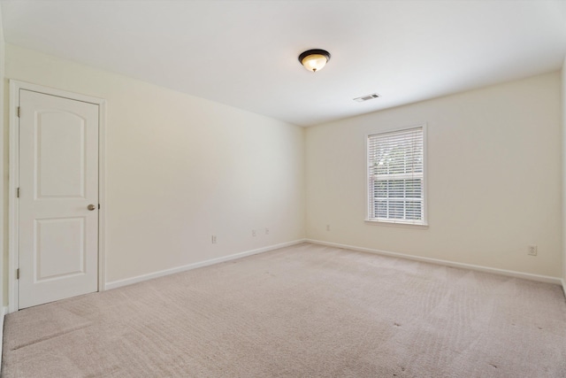 spare room featuring light carpet, baseboards, and visible vents