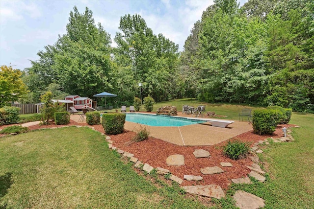 pool featuring a patio area, a diving board, and a lawn