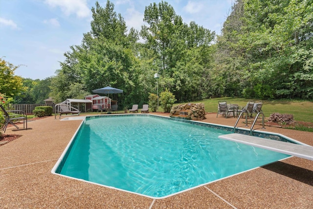 pool featuring a diving board, a yard, and a patio area