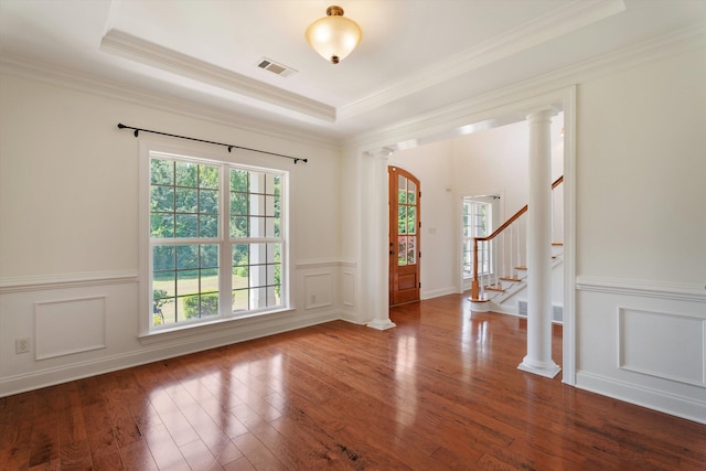 unfurnished room with a tray ceiling, visible vents, ornate columns, and wood finished floors