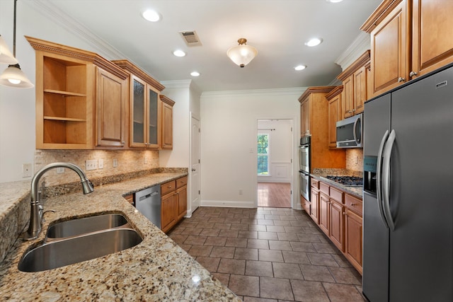 kitchen with light stone counters, crown molding, stainless steel appliances, brown cabinetry, and a sink