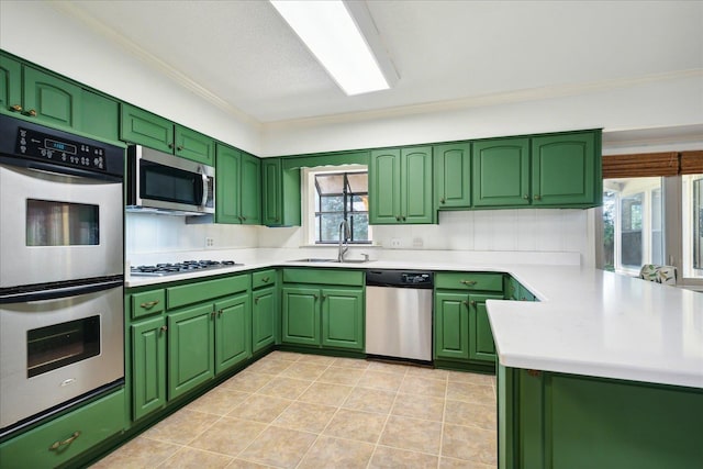 kitchen featuring a peninsula, green cabinets, stainless steel appliances, and a sink