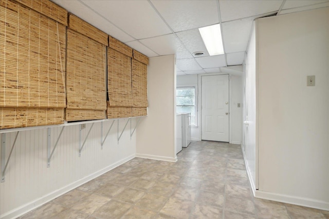 empty room with a drop ceiling and baseboards