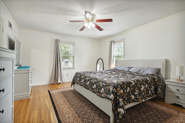 bedroom with a textured ceiling, ornamental molding, visible vents, and light wood-style floors