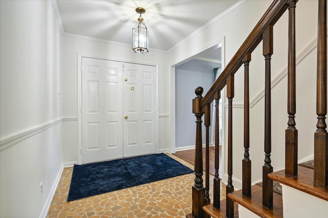 foyer entrance featuring baseboards, crown molding, stairway, and a textured ceiling