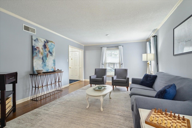 living room featuring a textured ceiling, ornamental molding, wood finished floors, and visible vents