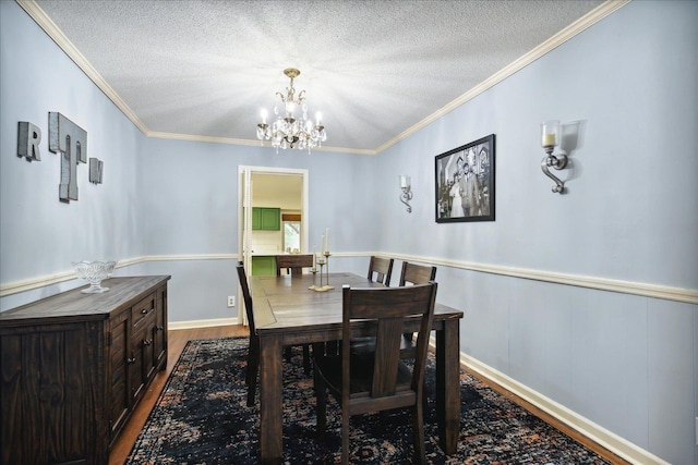 dining area with a textured ceiling, ornamental molding, a chandelier, and wood finished floors
