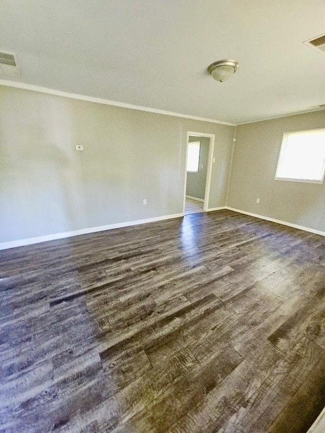 spare room featuring dark wood-style floors, baseboards, visible vents, and crown molding