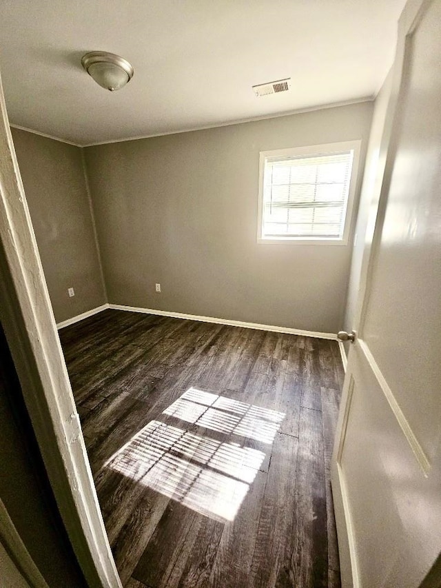 empty room with baseboards, visible vents, and wood finished floors