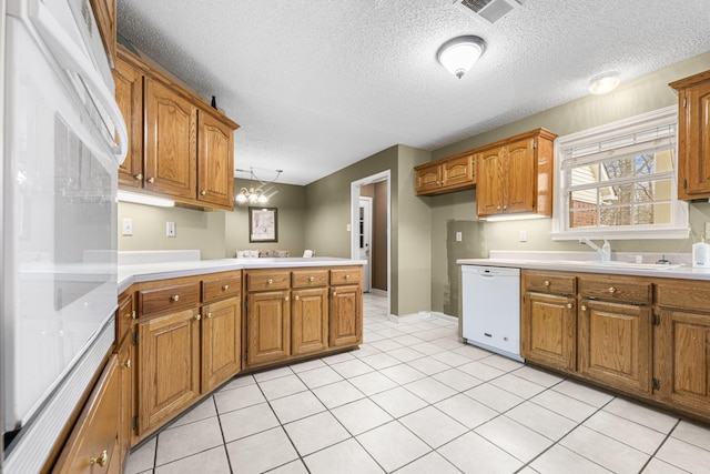 kitchen with brown cabinets, visible vents, dishwasher, and a peninsula