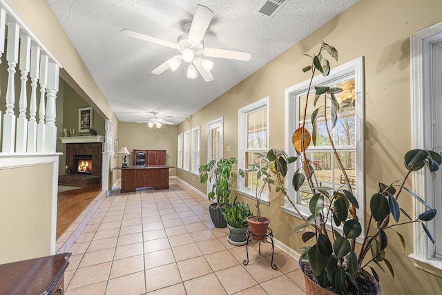 interior space with a brick fireplace, visible vents, and ceiling fan