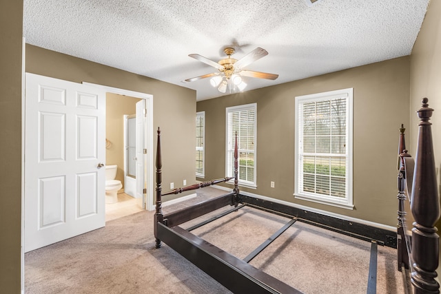 bedroom featuring baseboards, a ceiling fan, ensuite bath, a textured ceiling, and carpet floors