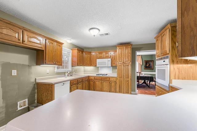 kitchen with white appliances, visible vents, light countertops, and a sink