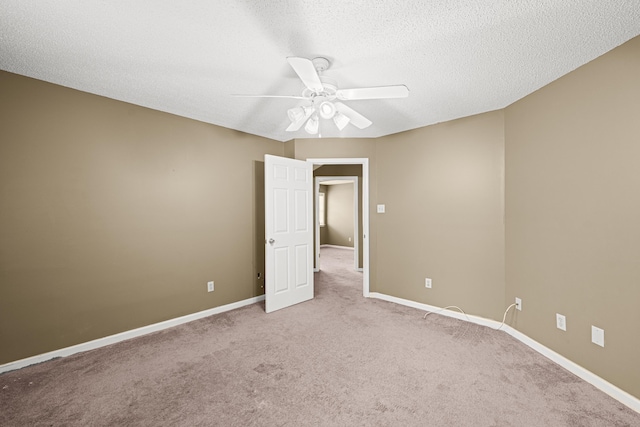 spare room featuring light carpet, ceiling fan, baseboards, and a textured ceiling