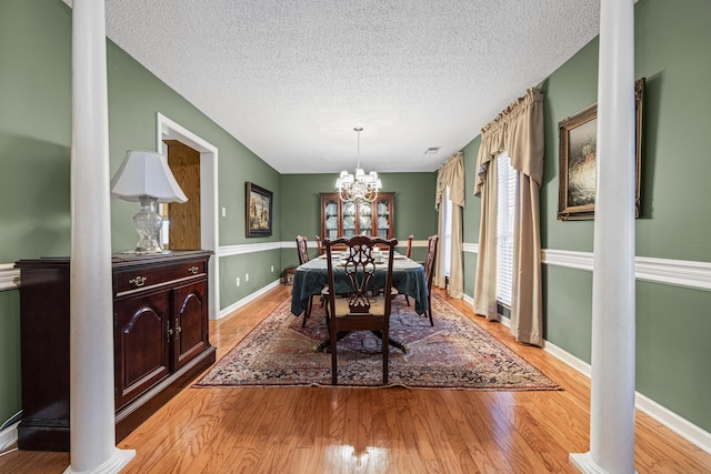 dining room with baseboards, light wood-style flooring, a chandelier, and a textured ceiling