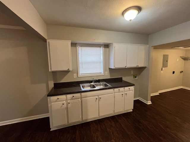 kitchen with dark wood-style floors, dark countertops, white cabinets, and a sink