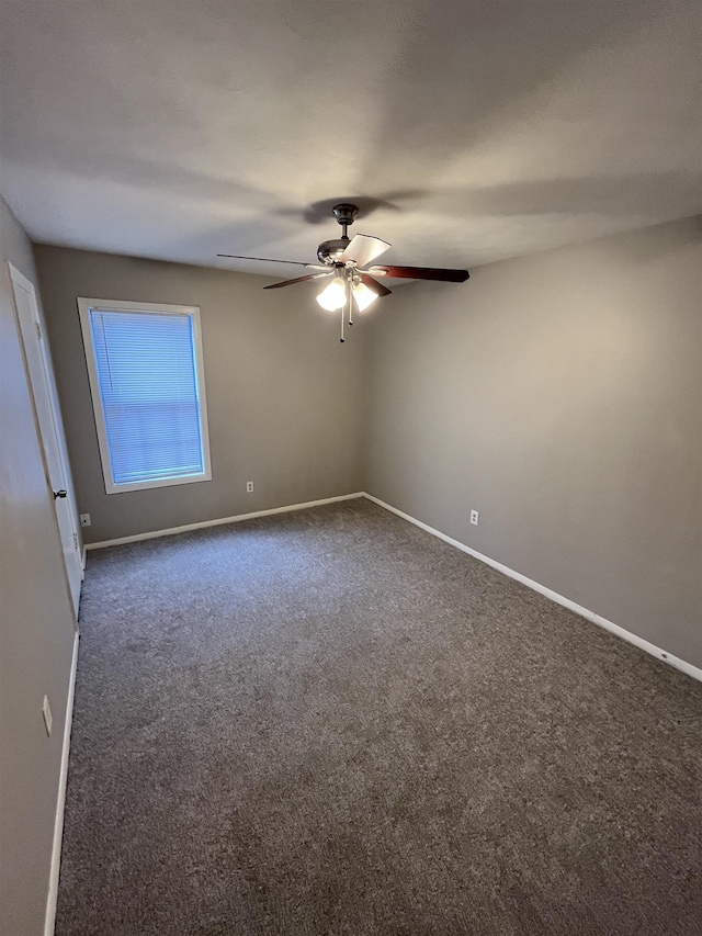 empty room featuring dark carpet, baseboards, and ceiling fan