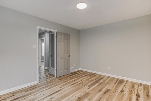 unfurnished room with visible vents, light wood-style flooring, and baseboards