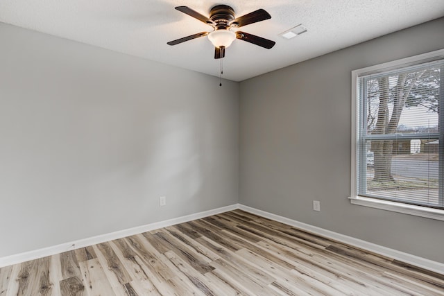 unfurnished room featuring a textured ceiling, visible vents, a ceiling fan, baseboards, and light wood-type flooring