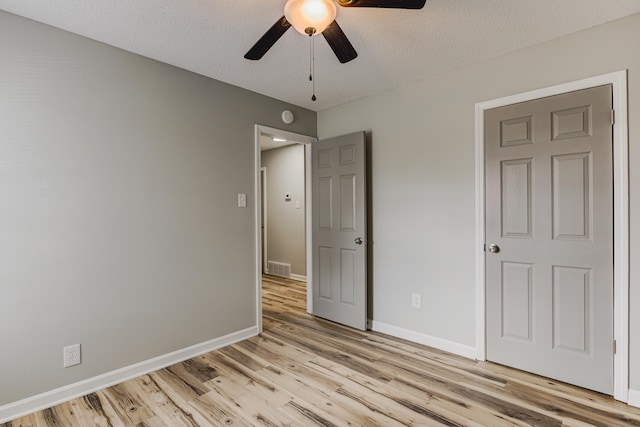 unfurnished bedroom with baseboards, a textured ceiling, visible vents, and light wood-style floors