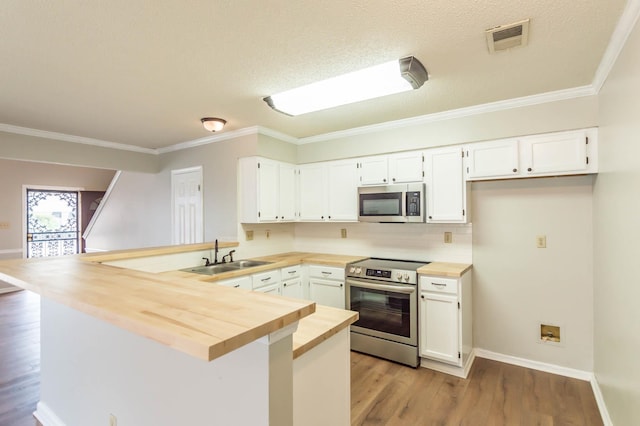 kitchen with visible vents, wood counters, a peninsula, stainless steel appliances, and a sink