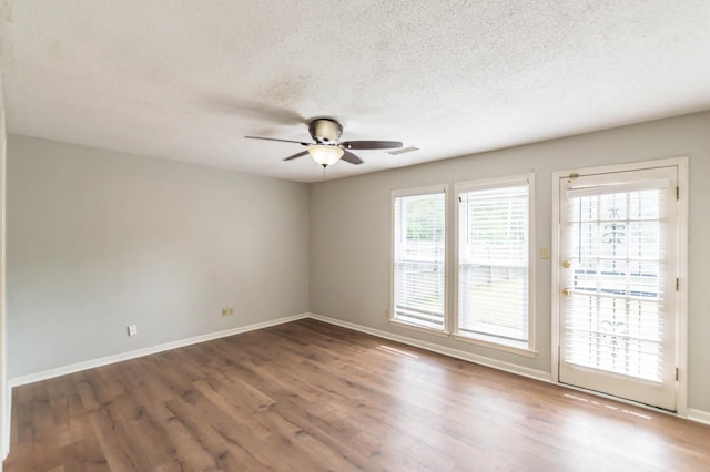 empty room with ceiling fan, a textured ceiling, wood finished floors, visible vents, and baseboards