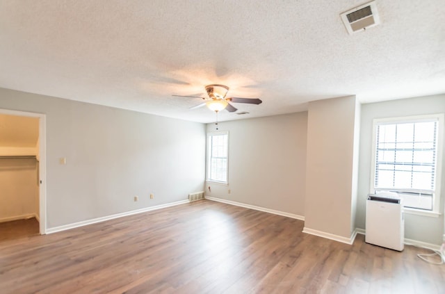 spare room with a ceiling fan, a textured ceiling, visible vents, and wood finished floors