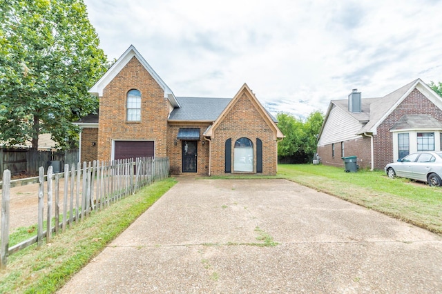 traditional-style home featuring a fenced front yard, brick siding, concrete driveway, an attached garage, and a front lawn