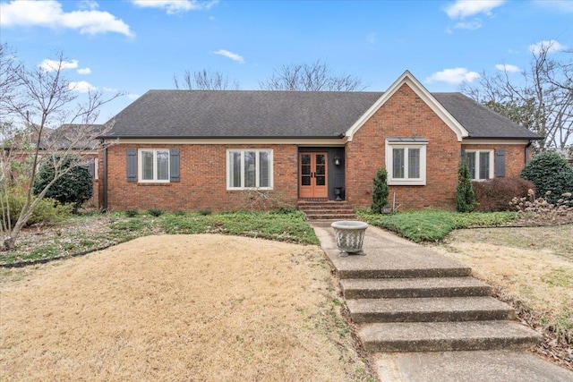 ranch-style home with entry steps, brick siding, and roof with shingles