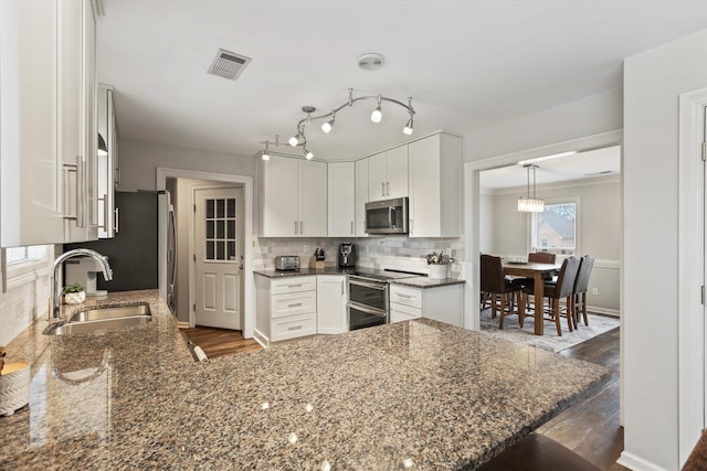 kitchen featuring a sink, visible vents, white cabinets, appliances with stainless steel finishes, and backsplash